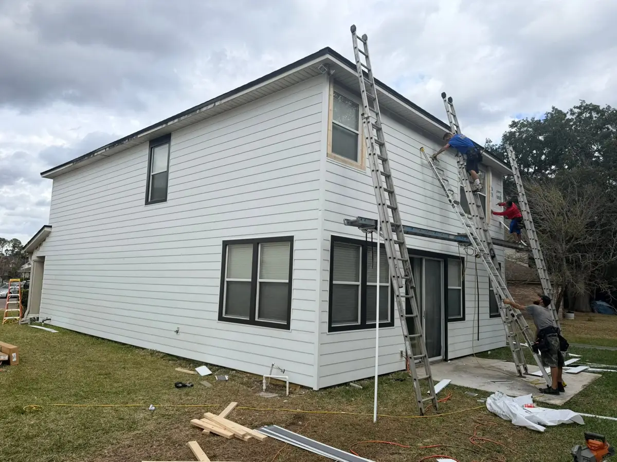 Crew installing siding on ladders