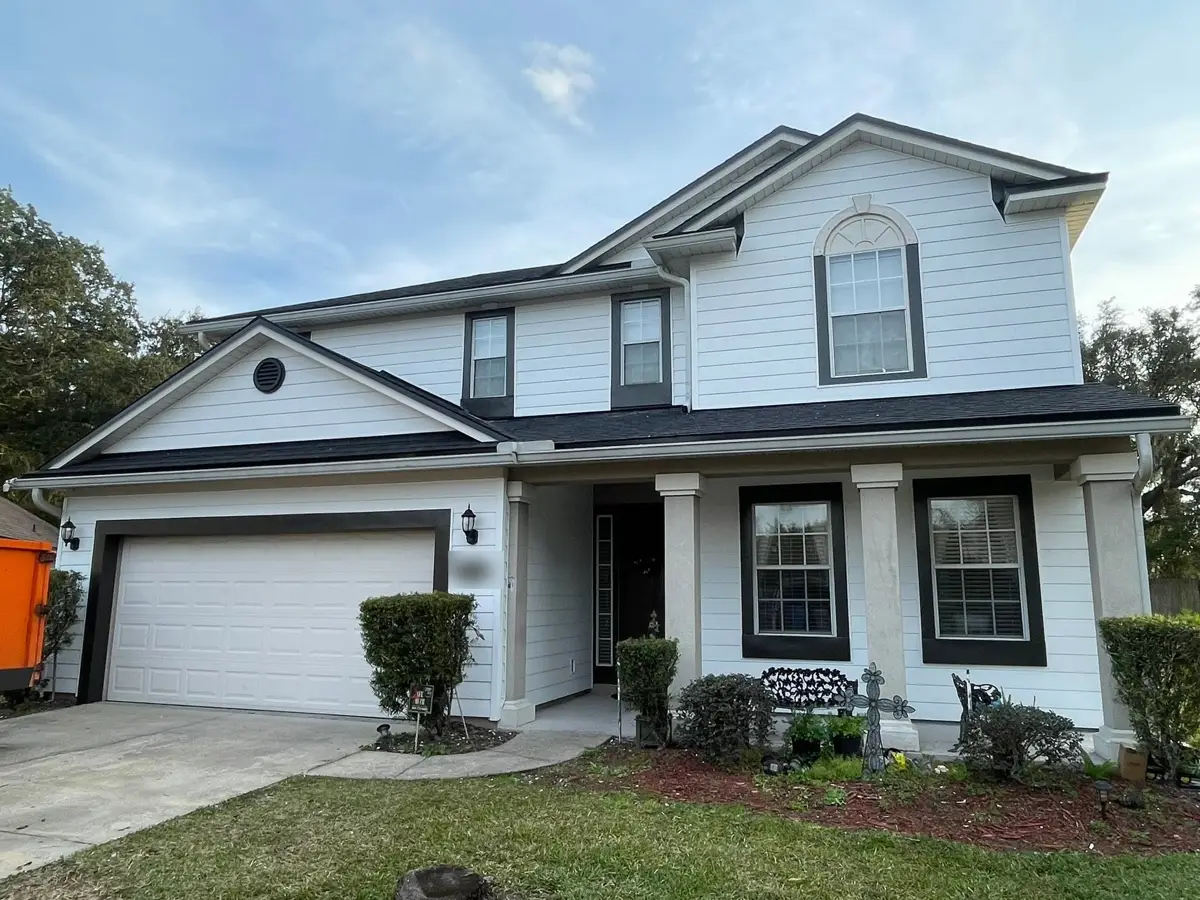 Two-story home finished in white siding with black window trim