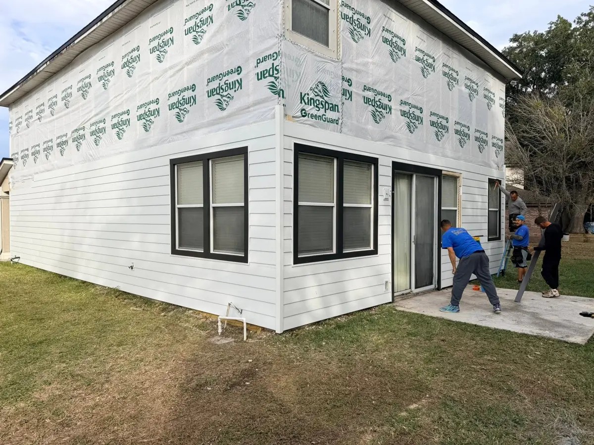 Home half covered in house wrap with siding started